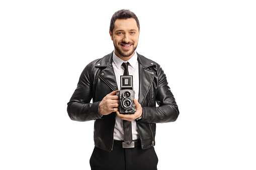 Handsome man smiling and holding a vintage camera isolated on white background