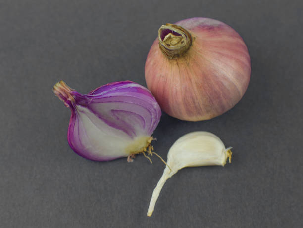 istock A half peeled pink colored onion placed beside a medium sized unpeeled onion and a piece of garlic before a black background 1215918890
