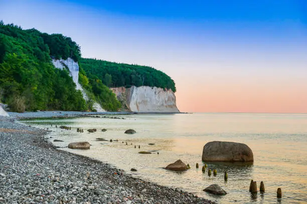 Sea coast and white cliffs on Rugen Island. Wooden breakwater on the beach. Dusk.