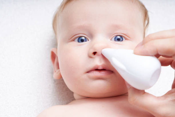 Mom cleans the nose of the baby with an aspirator Close up stock photo