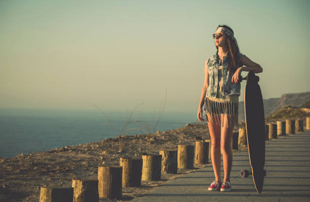 Beautiful and fashion young woman posing with a skateboard