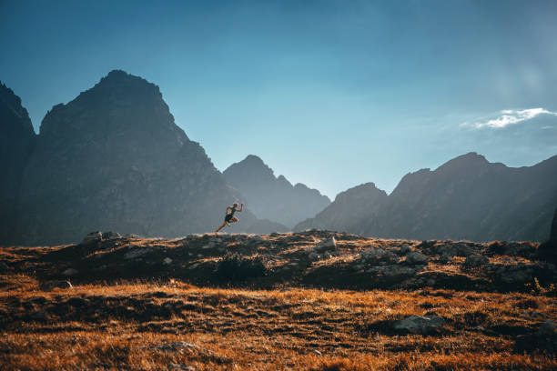 running in mountains. trail run photo, sunset light . man on yellow meadow under blue sky. - running jogging mountain footpath imagens e fotografias de stock
