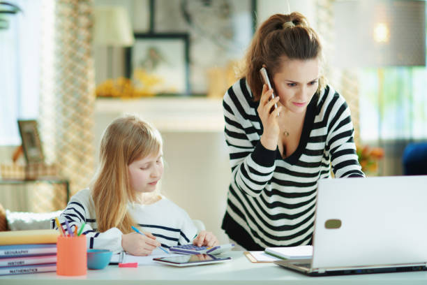 istock mother talking on phone and working while child doing homework 1215925685