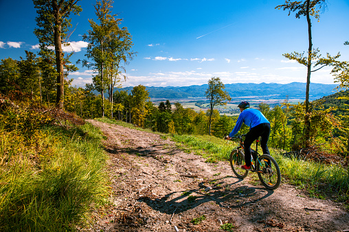 Mountain biking man riding downhill on bike at autumn mountains forest landscape. Outdoor sport activity. Colorful nature.