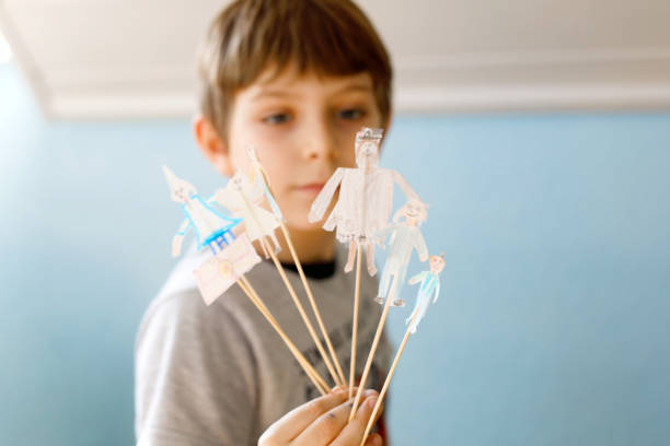 School kid boy making paper doll theatre
