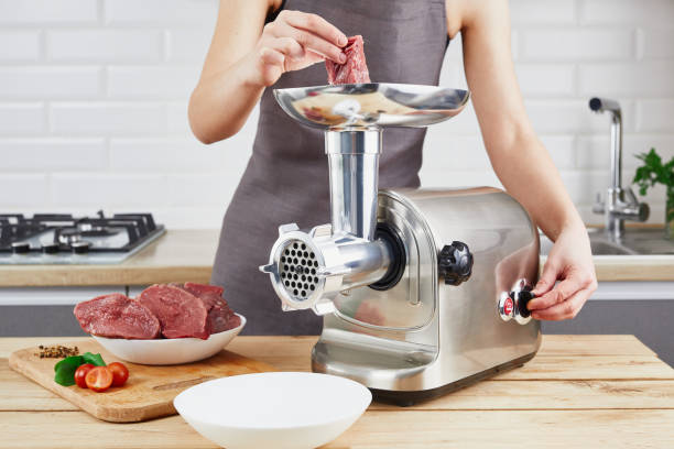 Raw meat. The process of preparing forcemeat by means of a meat grinder. Female hands use meat chopper at kitchen. The process of preparing forcemeat by means of a meat grinder. Female hands use meat chopper at kitchen. grinding metal power work tool stock pictures, royalty-free photos & images