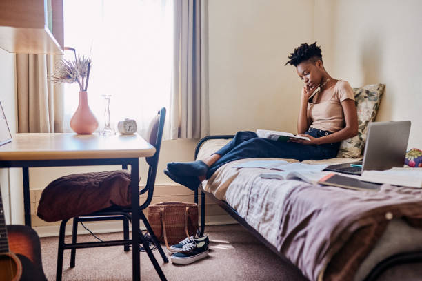 Theory requires focus Shot of an attractive young female university student reading a textbook in her room dorm room photos stock pictures, royalty-free photos & images