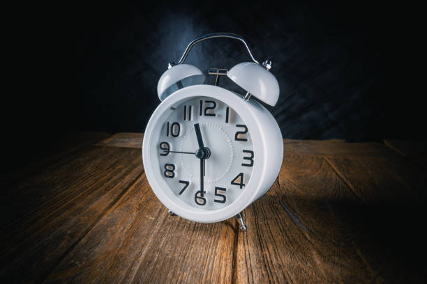 istock retro alarm clock on wood table with dark background 1215928956