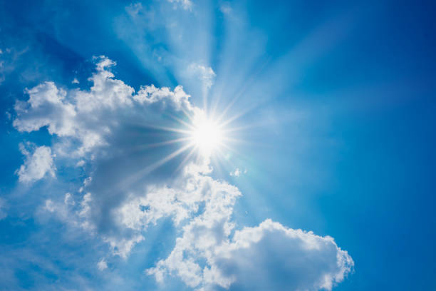 istock blue sky with clouds and sun shines bright in the day 1215929052