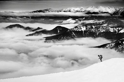 Skier on the horizon with mist and mountains landscape in his background.