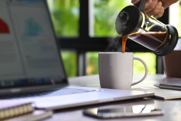 istock A hand pouring steaming coffee in to a cup on a work desk when work from home 1215931280