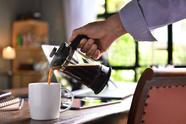 istock A hand pouring steaming coffee in to a cup on a work desk when work from home 1215931306