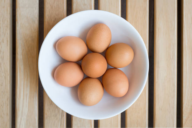 istock Eggs with brown shells in ceramic bowl on a brown wooden table 1215933375