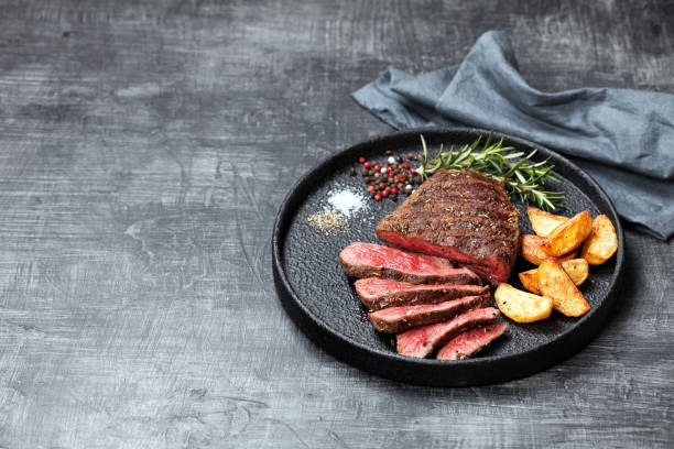 sliced medium rare grilled beef steak and potato wedges - close up roasted meal pepper imagens e fotografias de stock