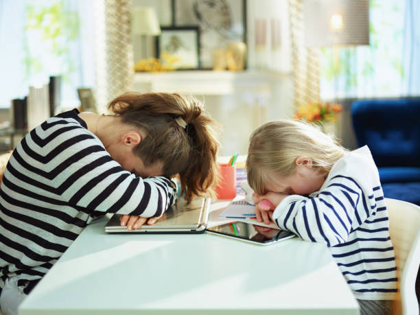 stanca giovane madre e bambino sdraiato sul tavolo - furniture internet adult blond hair foto e immagini stock