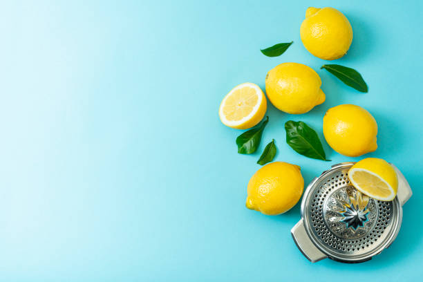 Ripe lemons flat lay with leaves on blue background