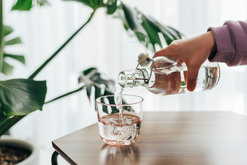 Woman Pouring Water from Bottle to Glass