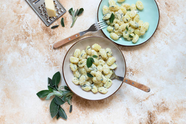 Italian homemade gnocchi with butter, cheese and sage served in two plates on a light marble table. Italian food. Copy space. Flat lay Italian homemade gnocchi with butter, cheese and sage served in two plates on a light marble table. Italian food. Copy space. Flat lay ricotta stock pictures, royalty-free photos & images