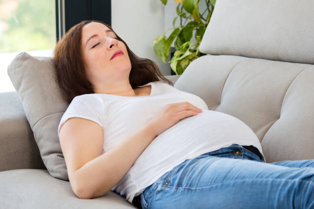 istock pregnant woman napping on sofa 1215945431