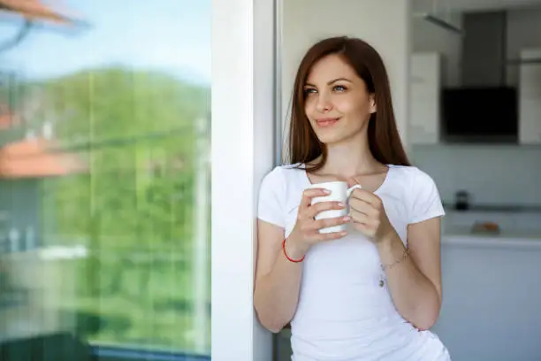 Photo of Young woman enjoying coffee at home