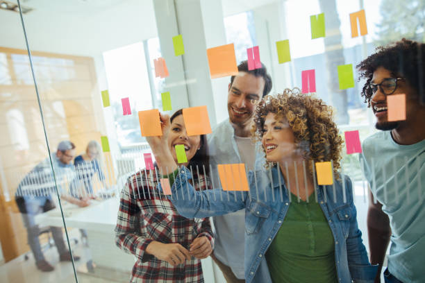 Business team brainstorming in front of glass wall Business team brainstorming in front of glass wall with adhesive notes writing on chalk board stock pictures, royalty-free photos & images
