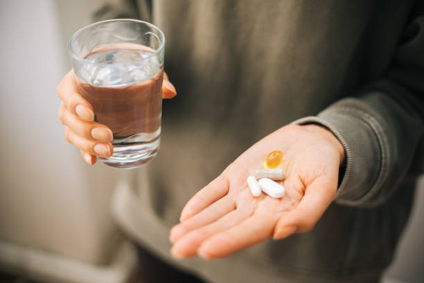 una mano sosteniendo un montón de píldoras en una palma abierta - vitamin pill vitamin c nutritional supplement bottle fotografías e imágenes de stock