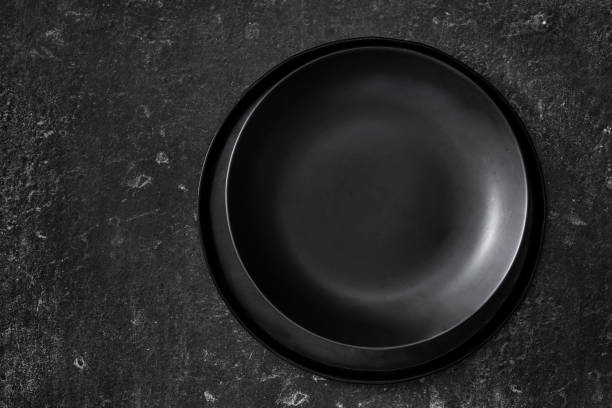 istock Top view of empty black plates on black background 1215954535