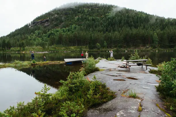 July 7, 2012 - Norway: recreational, leisure and healthy time - father, sons, grandfather, grandmother fishing together on a lakeshore and rocks in Norway