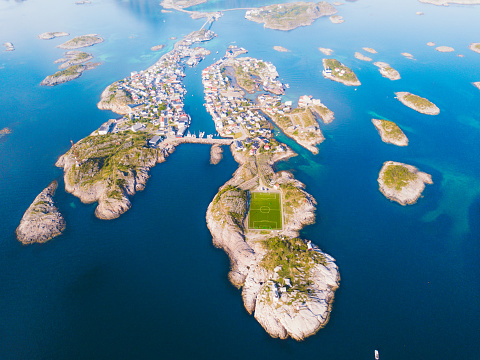 Drone panoramic photo of sunny bright summer day at the beautiful village located on the sea at the different small islands with Mountain View and the football field at the edge of the world