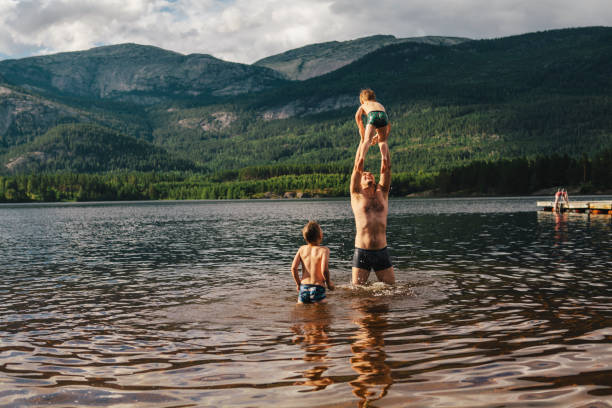istock A father is lifting his son, ready to throw him into water on a summer day in Norway, while another boy, a brother, is looking and waiting for his turn, all laughing and being happy 1215957404