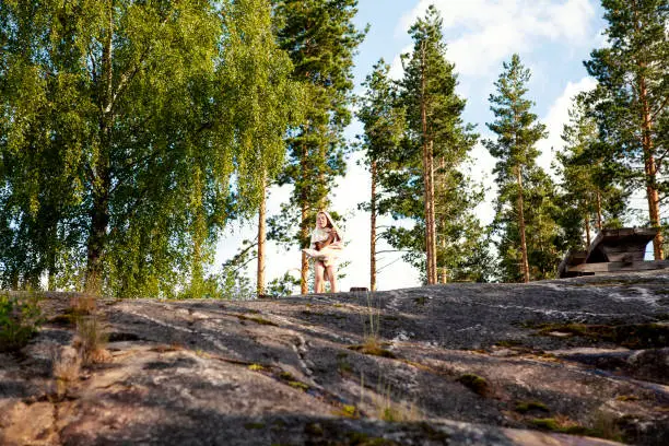 June 28, 2013 - Norway: funny beautiful little boy making fun - singing, dancing, grimacing - high up on a rock wrapped in a towel after a swim in a lake in Norway