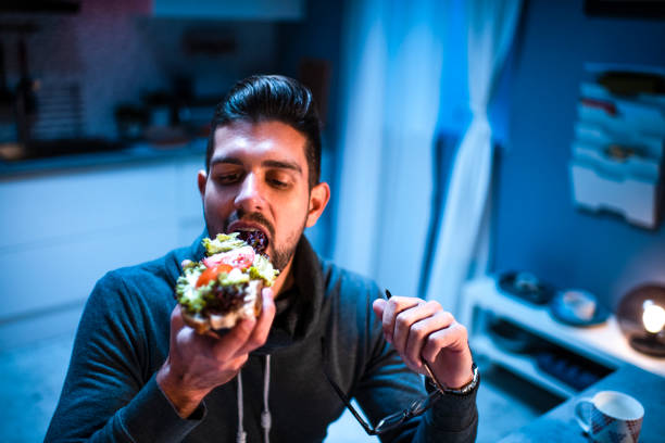 istock A young man having a sandwich late at night while working from home 1215960974