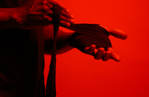 Read filtered shot of a sporty young man wrapping his hands before boxing