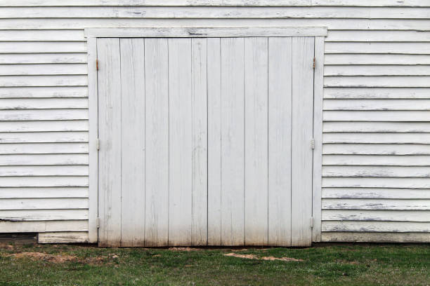 istock faded white wooden warehouse building doorway grass 1215967052