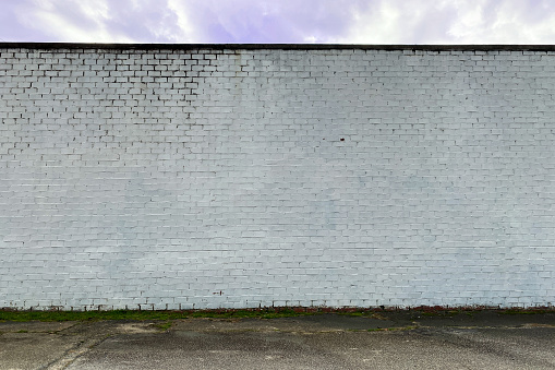 a white faded stone brick factory warehouse wall in an alley