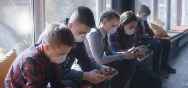 스마트폰을 사용한 페이스 마스크 착용 학생 - telephone window mobile phone addiction 뉴스 사진 이미지
