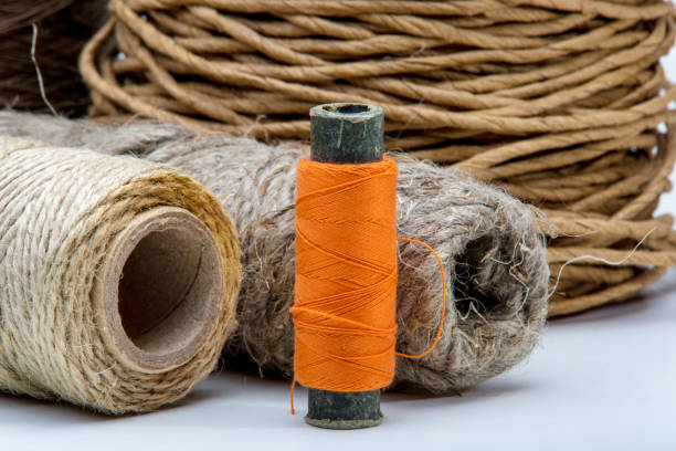image of a spool of orange thread on a background of rough twine