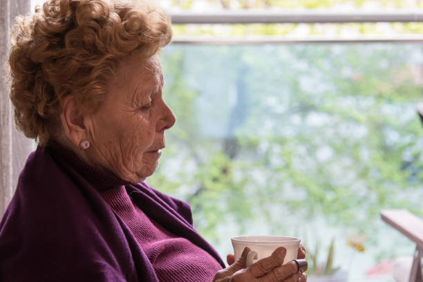istock Elderly woman sitting by the window having a coffee 1215974532
