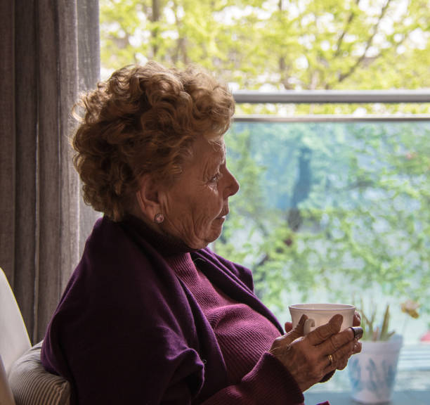 istock Elderly woman sitting by the window having a coffee 1215975052