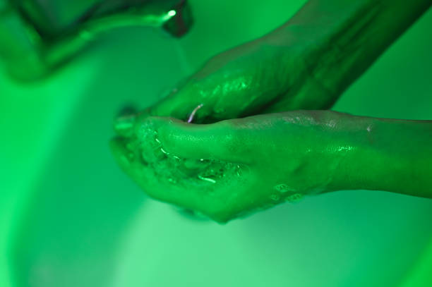 istock washes his hands on a green background. close-up. On a black background. The concept of coronavirus. Hand washing and hygiene concept 1215975372