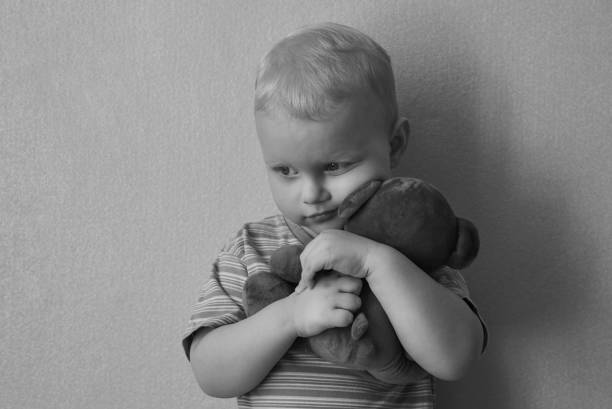 istock Little lonely boy hugs his teddy bear strongly. 1215976057