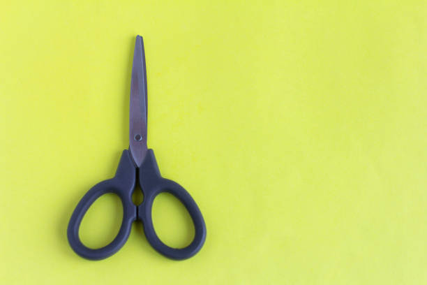 istock Black scissors on a yellow background.Small scissors for cutting. 1215977361