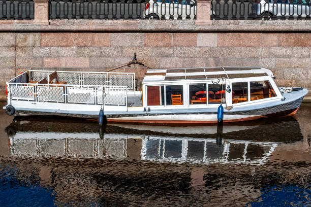 View of a pleasure boat parked on the granite embankment of the Moika river in Saint Petersburg.