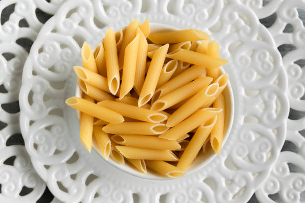 Dry penne pasta on blue white vintage plate, whole wheat uncooked ingredient, space for text