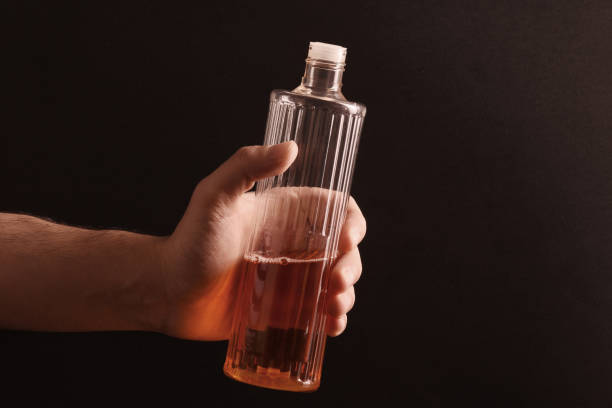 A male hand holding eau de cologne bootle on black background