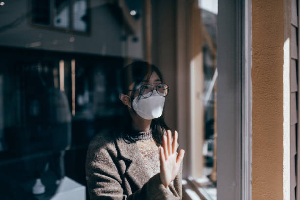 istock Woman behind the Window with Mask 1215982048