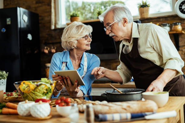 istock Mature couple using digital tablet while cooking together in the kitchen. 1215984472