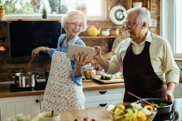 istock Happy senior couple having fun while using touchpad and cooking in the kitchen. 1215985506