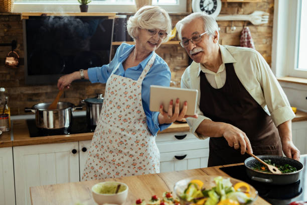 istock Mature couple following recipe on digital tablet while preparing lunch in the kitchen. 1215985689