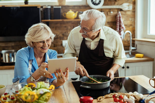 istock Happy mature couple having fun while using touchpad and cooking in the kitchen. 1215985914